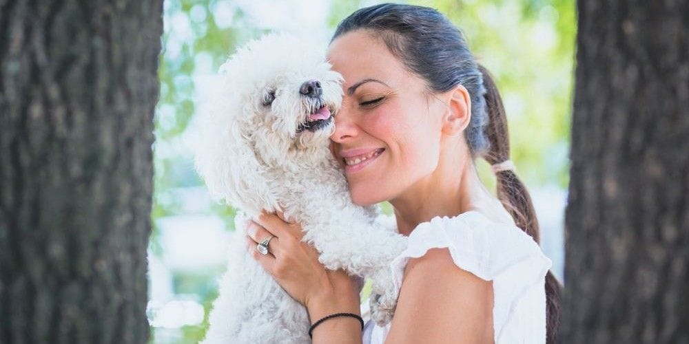 Woman holding her client's dog in the park.