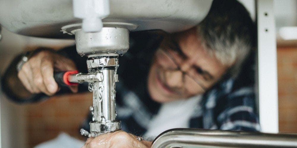 Plumber fixing leaky pipe.